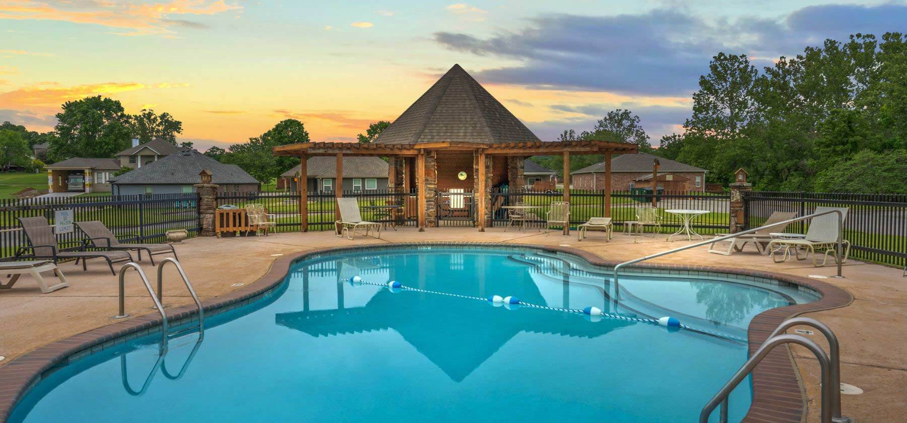 Community pool with loungers and a pavilion at twilight.