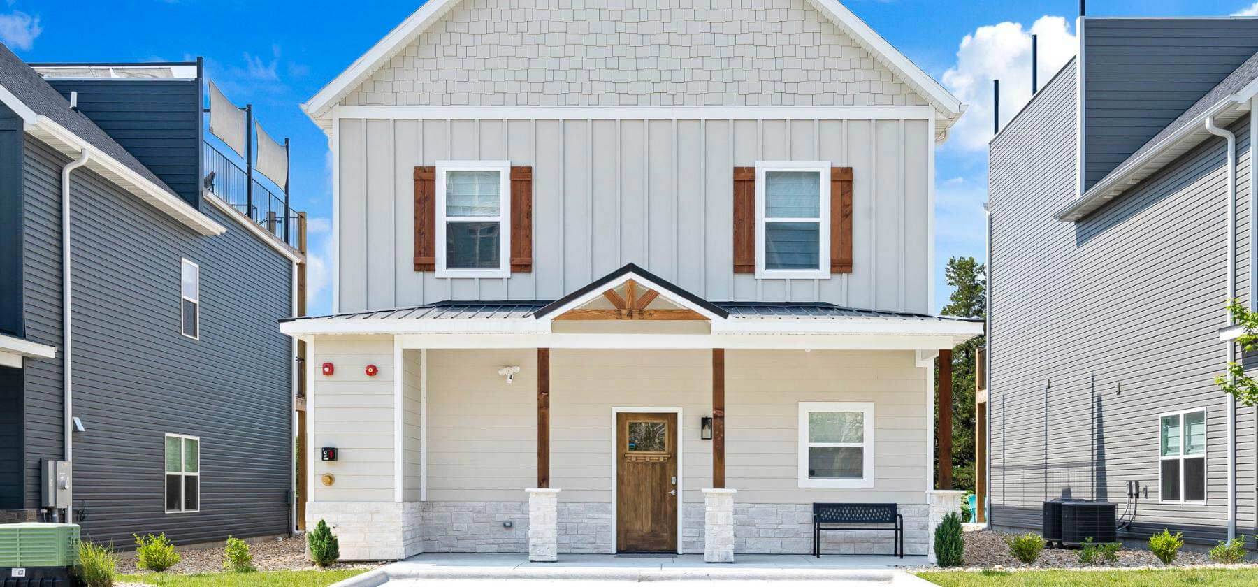 New two-story house with white siding, a gray roof, and a wooden front door.
