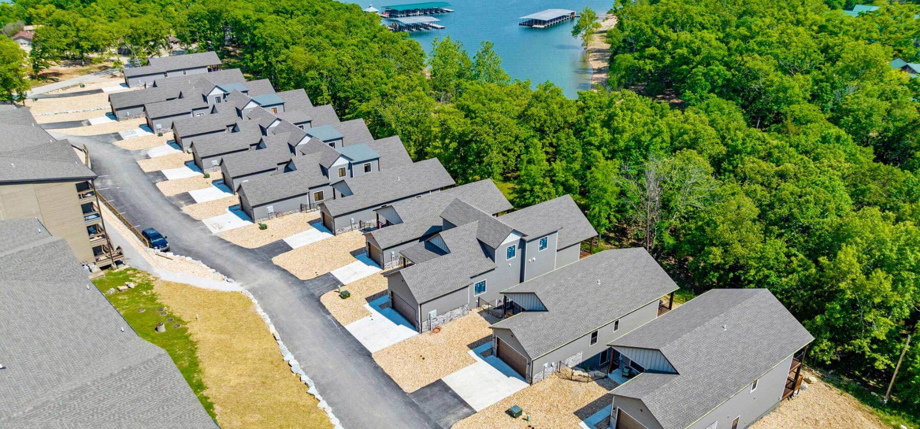 Aerial view of a suburban neighborhood with houses near a forest by a lake with docks.